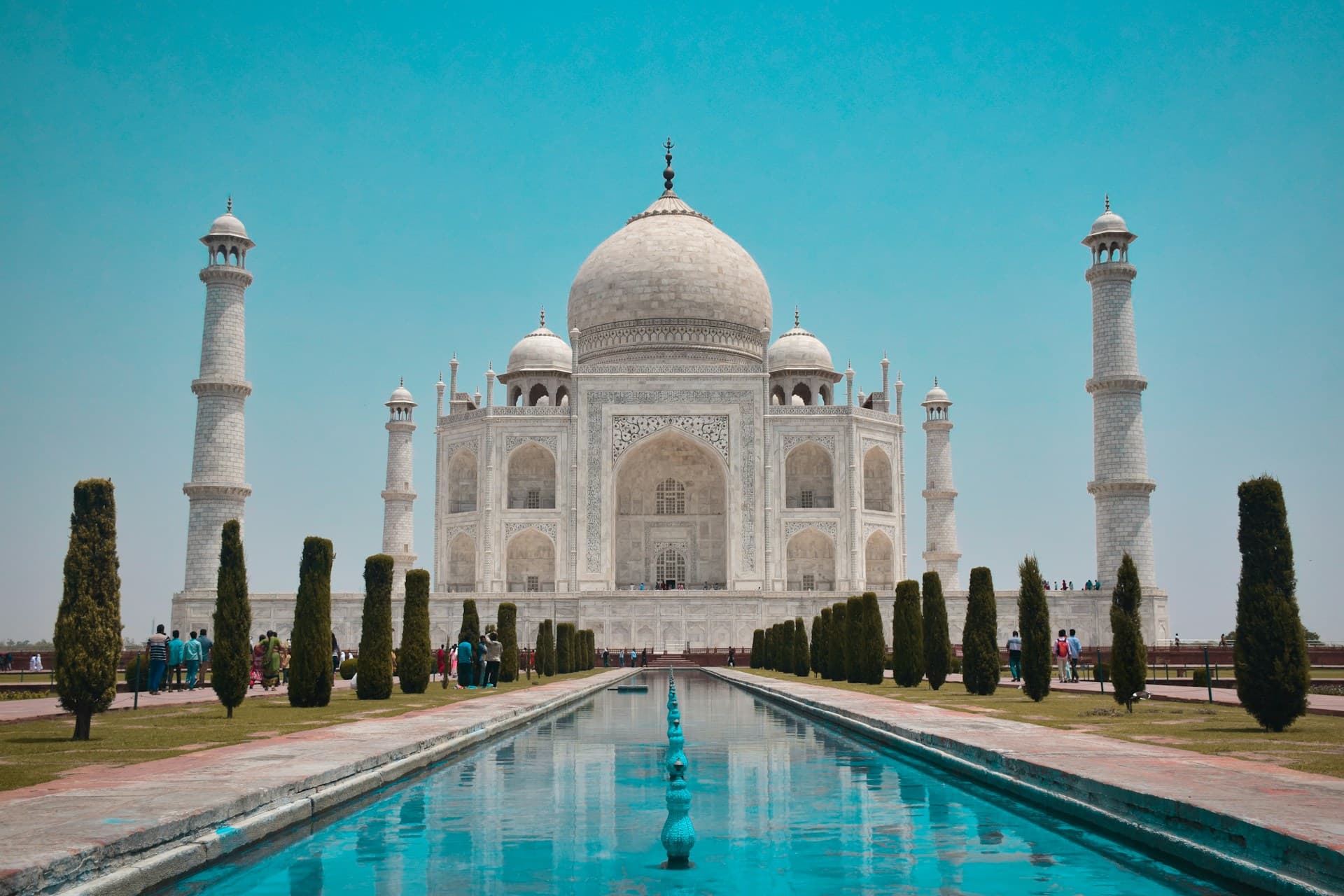 The Taj Mahal reflected in a long pool at sunrise